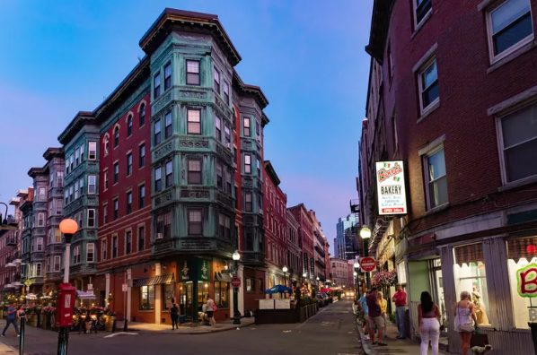 A multi-story building with a distinctive corner entrance on a city street at dusk.