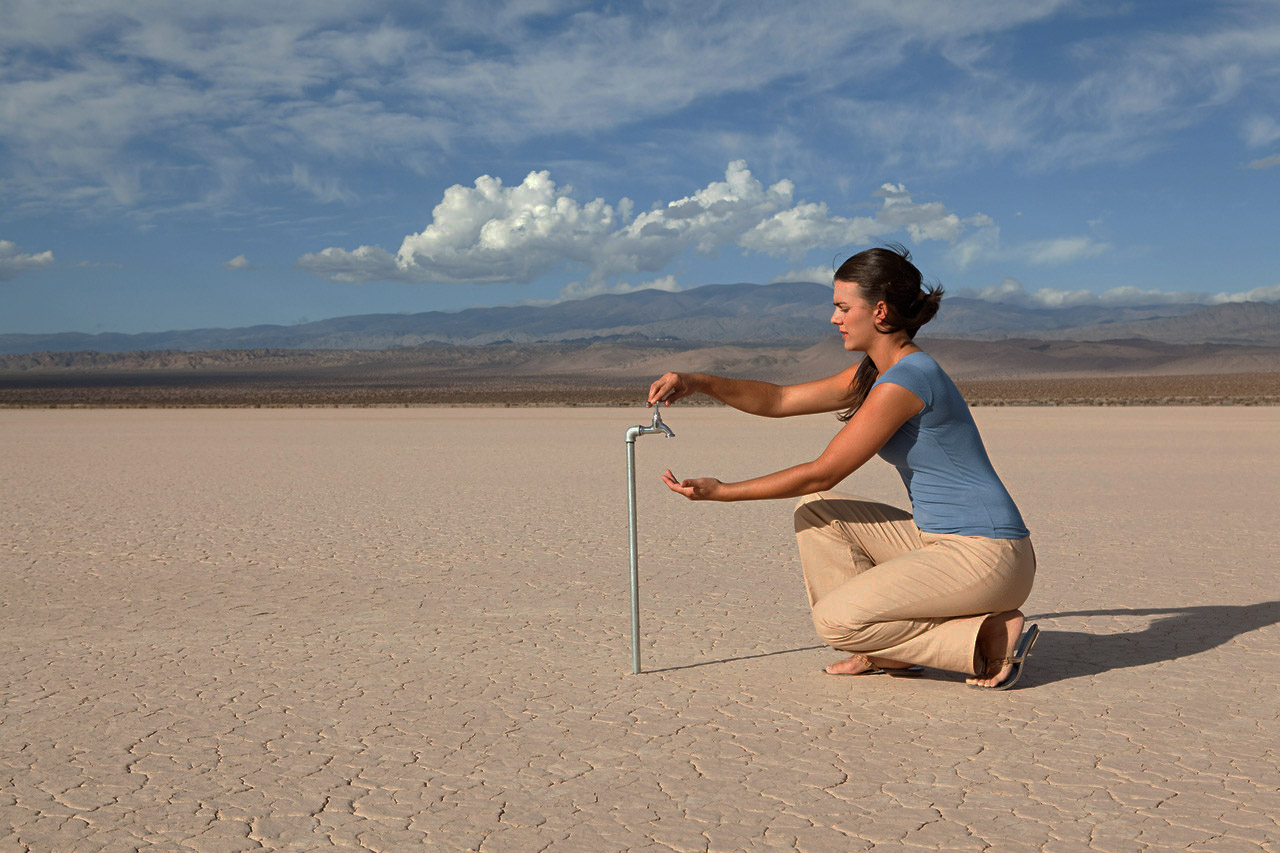 Woman looking for water at a tap in a desert area