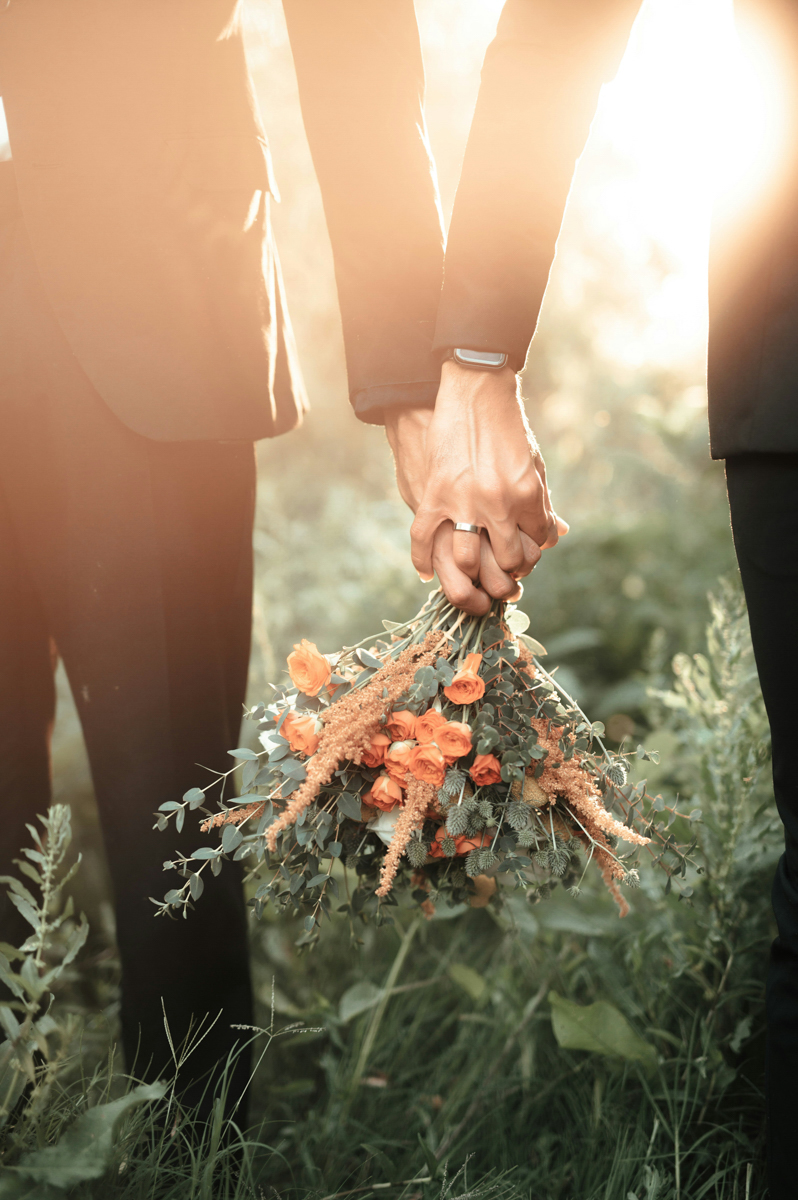 A couple holding hands and a bouquet of flowers