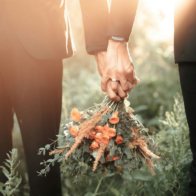 A couple holding hands and a bouquet of flowers