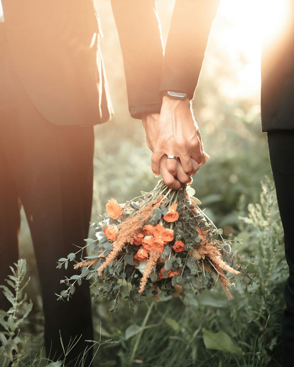 A couple holding hands and a bouquet of flowers
