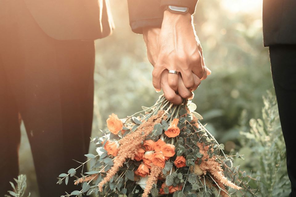 A couple holding hands and a bouquet of flowers