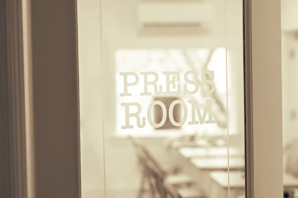 Black and white image of a door with Press Room written on the front