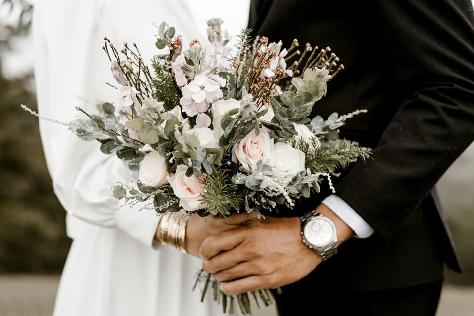 Bride and groom holding a bouquet of flowers on their wedding day