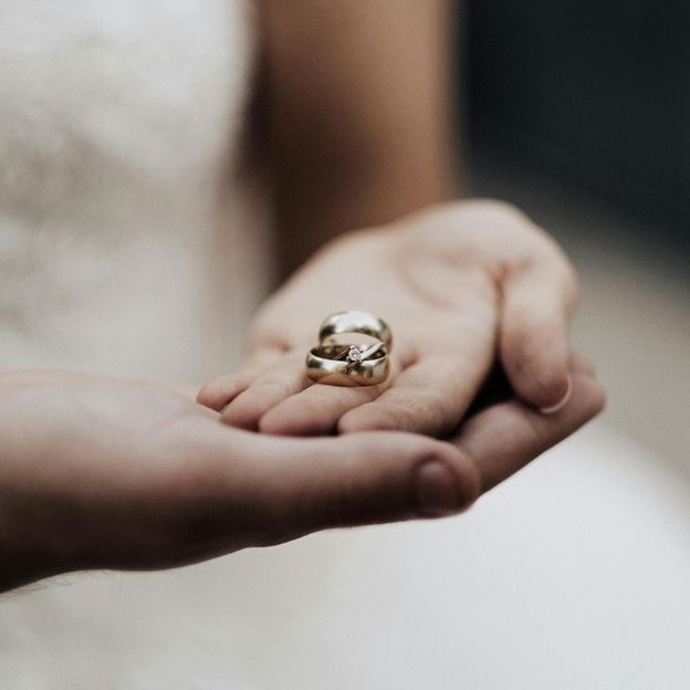 Bride and groom holding their wedding rings in their hands