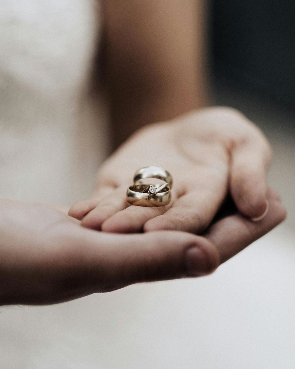 Bride and groom holding their wedding rings in their hands