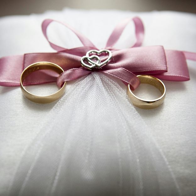 Wedding rings tied together with a ribbon on a white pillow