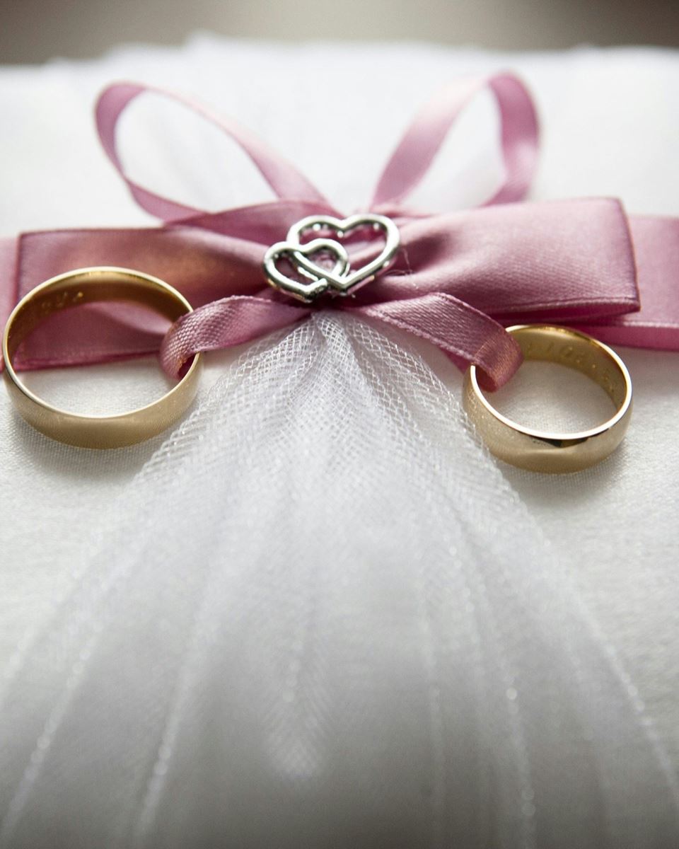 Wedding rings tied together with a ribbon on a white pillow