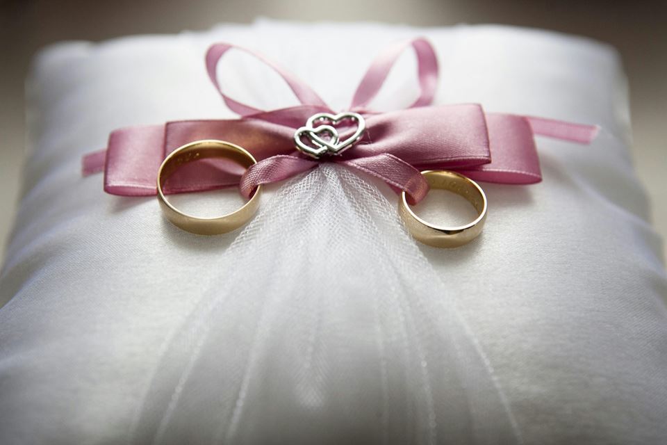 Wedding rings tied together with a ribbon on a white pillow